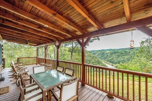 Eine Holzterrasse mit Tisch und Stühlen aus Glas, mit Blick auf ein Tal.
