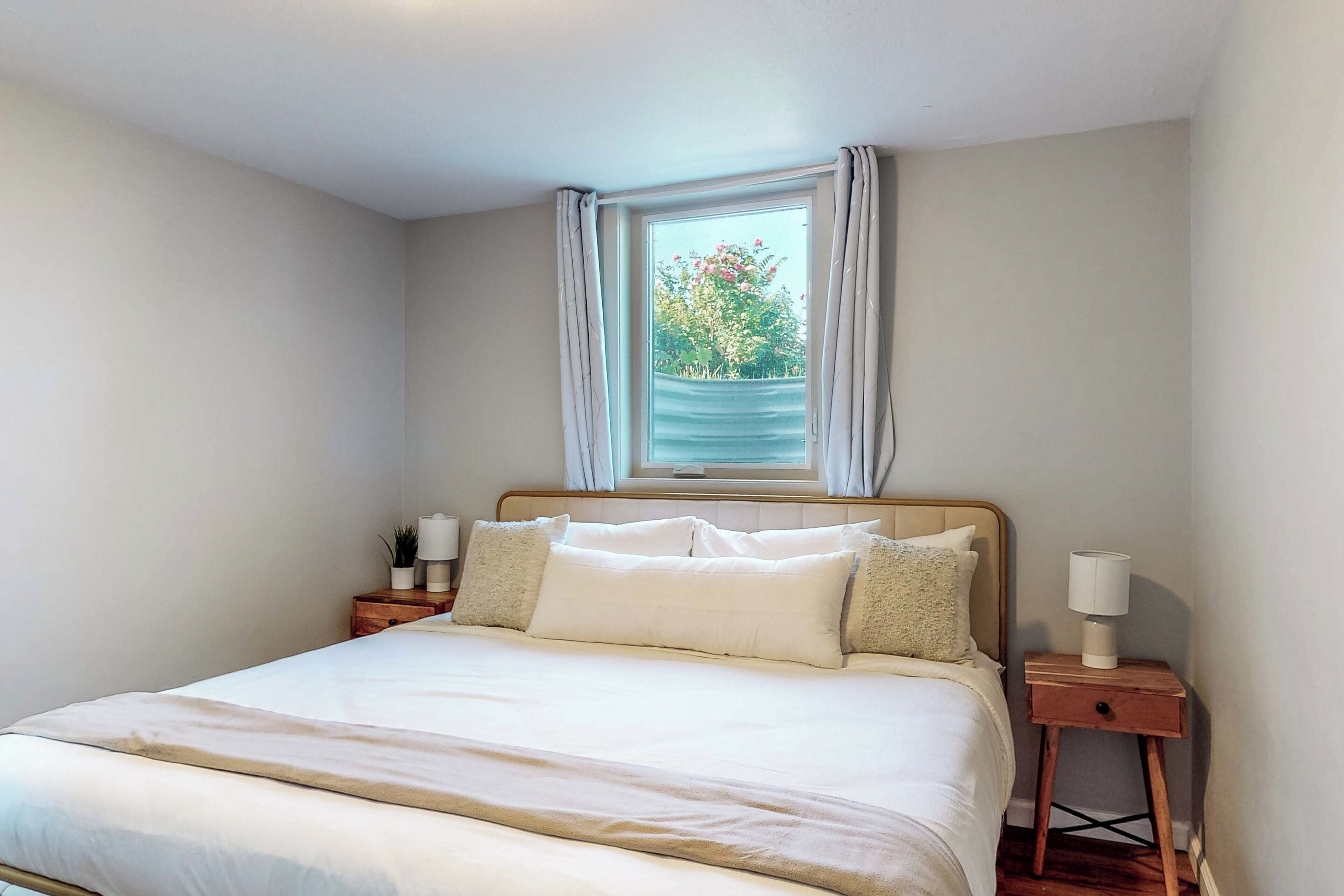 A neatly made bed with white linens, a wooden headboard, and two bedside tables with lamps.