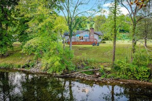 A house with a deck and a pond in the foreground. - Riverfront Angler's Oasis in Elizabethton (Elizabethton)