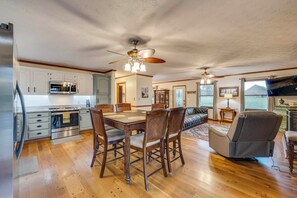A spacious kitchen with modern appliances, a dining area with wooden chairs, and a living room with a sofa and television. - Riverfront Angler's Oasis in Elizabethton (Elizabethton)