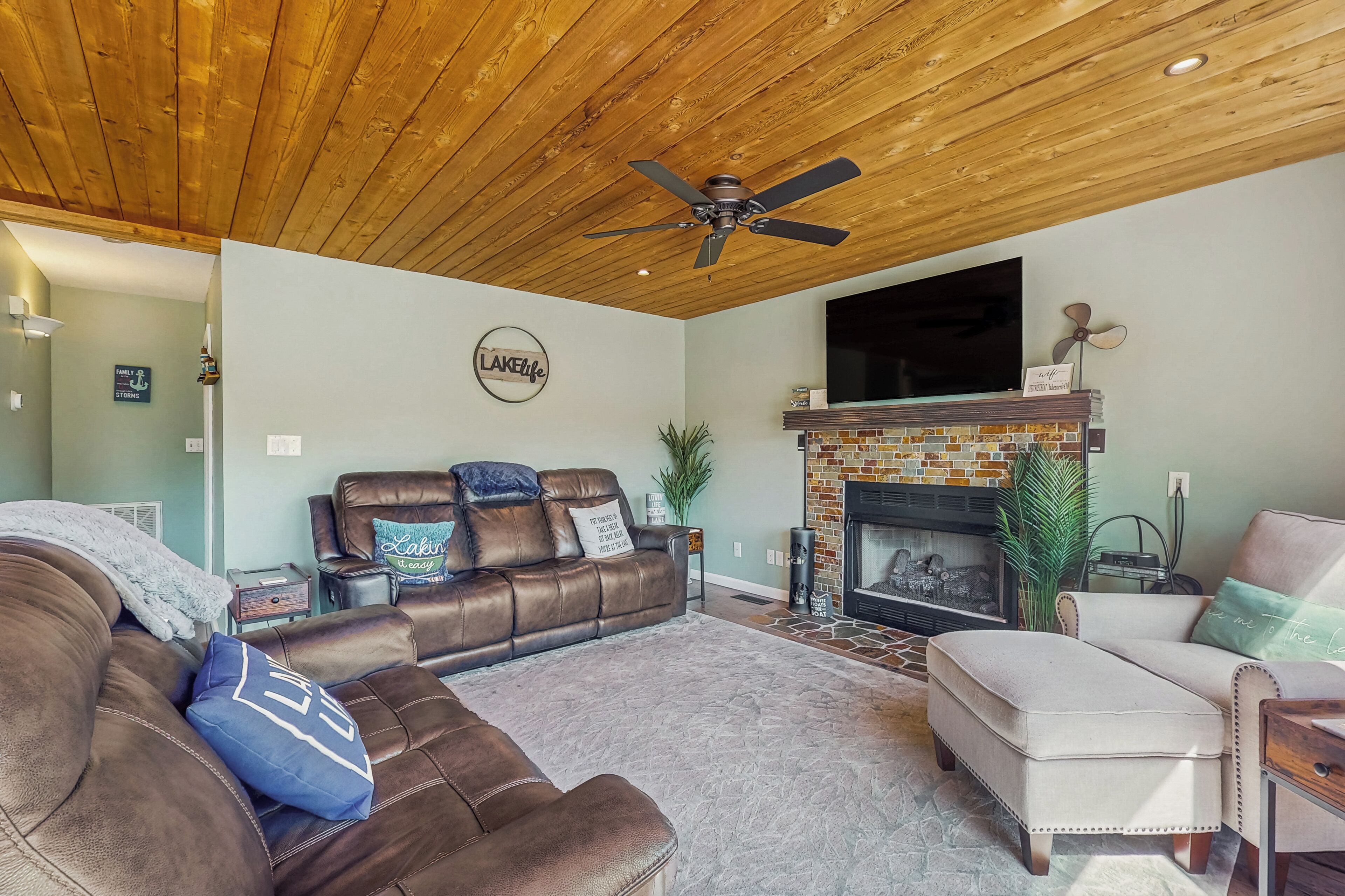 Una sala de estar con chimenea, sofás de cuero y ventilador de techo.