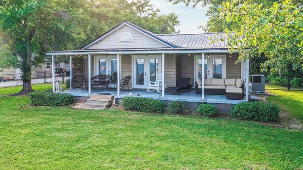 A single-story house with a covered porch, a patio with outdoor furniture, and a small garden area. - 2BR Lakefront Getaway w/ Dock & Boat Launch (Bonneau)