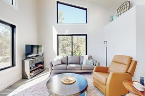 Una sala de estar moderna con un sofá, una mesa de centro y un televisor sobre un mueble.
