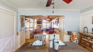 A dining area with a wooden table set for four, a ceiling fan, and a view into the kitchen. - 'harbor Haven' w/ Dock: Lake Livingston Home (Livingston)