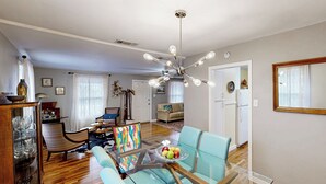 Ein modernes Wohnzimmer mit einem Glastisch, blauen Stühlen und einer Deckenleuchte.