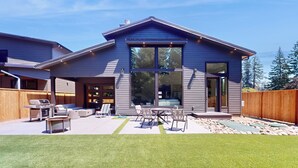 A modern house with a large patio, outdoor seating, and a barbecue area. - 5BR Home w/ Nearby Lake, A/C & Private Backyard (Detroit)