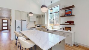 A modern kitchen with a large island, white cabinetry, and pendant lighting. - 5BR Home w/ Nearby Lake, A/C & Private Backyard (Detroit)