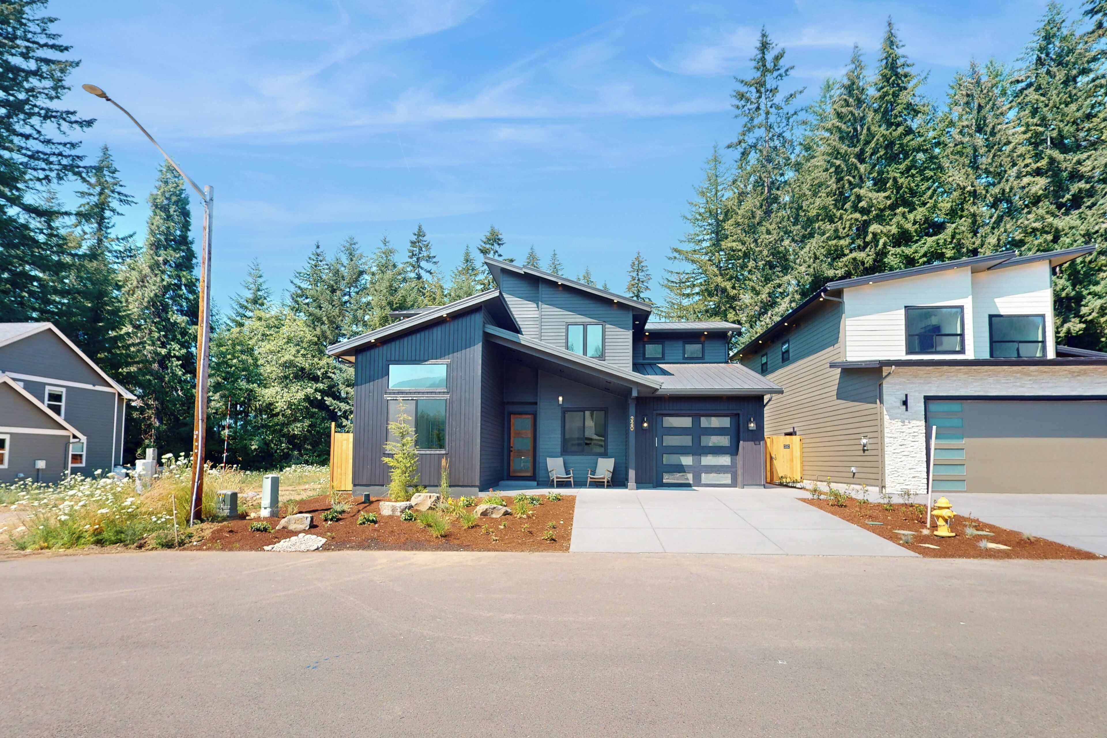 A modern two-story house with a garage, a driveway, and a landscaped front yard.