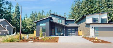 A modern two-story house with a garage, a driveway, and a landscaped front yard.