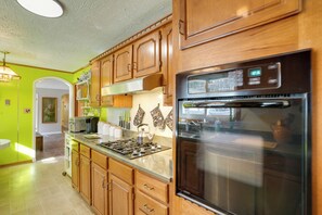 A kitchen with wooden cabinets, a stainless steel refrigerator, and a gas stove. - Hike & Ski: Scenic Group Retreat in Wardensville (Wardensville)