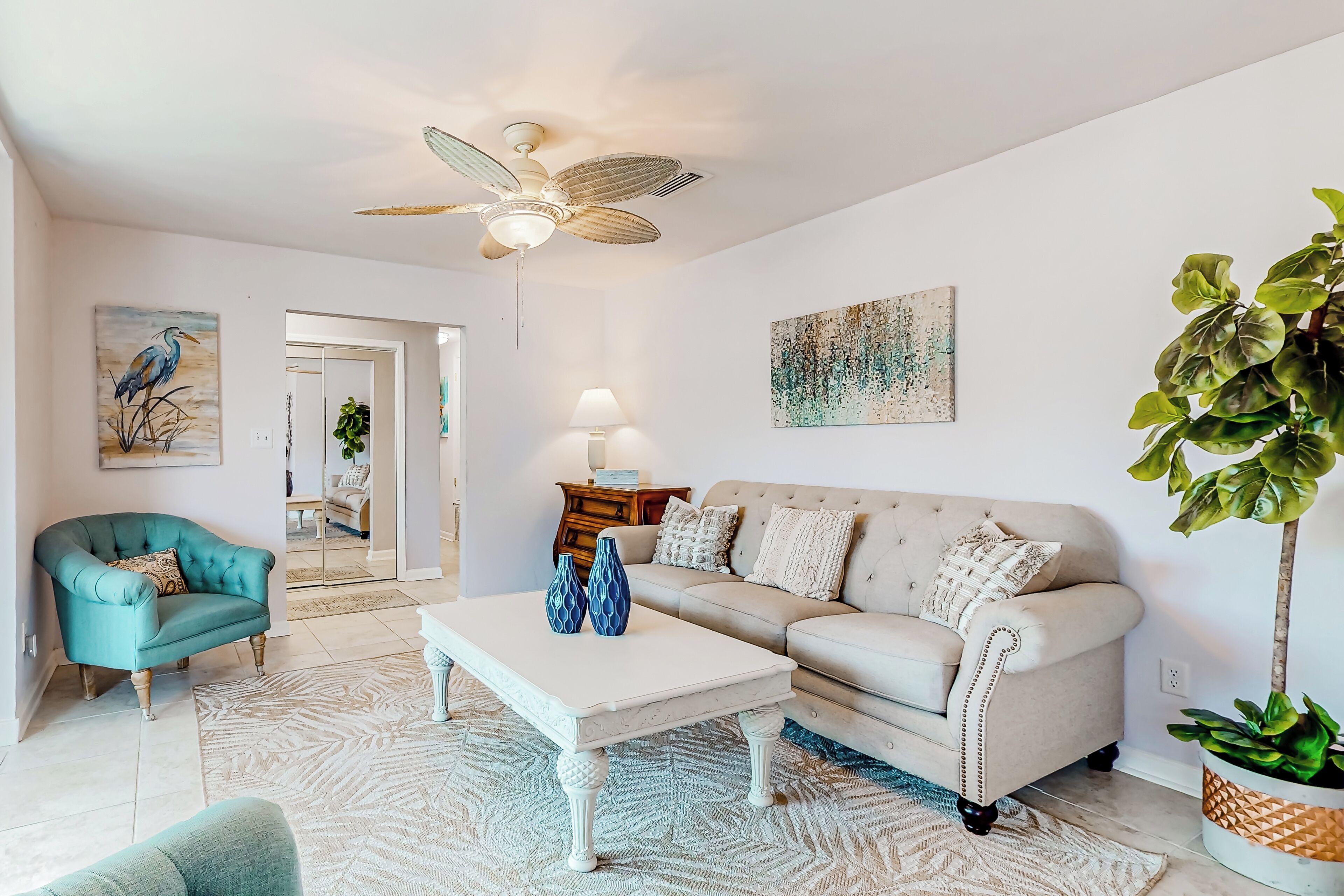 Una sala de estar con sofá, sillón, mesa de centro y ventilador de techo.