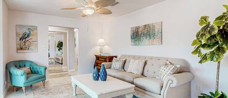 Un salon comprenant un canapé, un fauteuil, une table basse et un ventilateur de plafond.