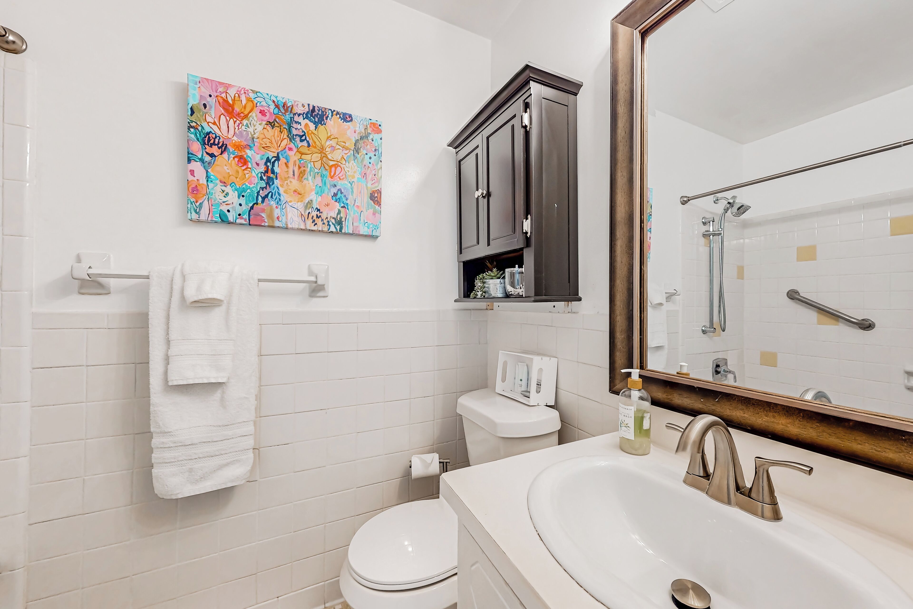 A bathroom with a white sink, a mirror, a toilet, and a cabinet.