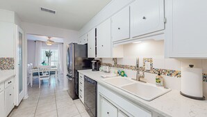 A modern kitchen with white cabinetry, a central island, and a dining area with a table and chairs.