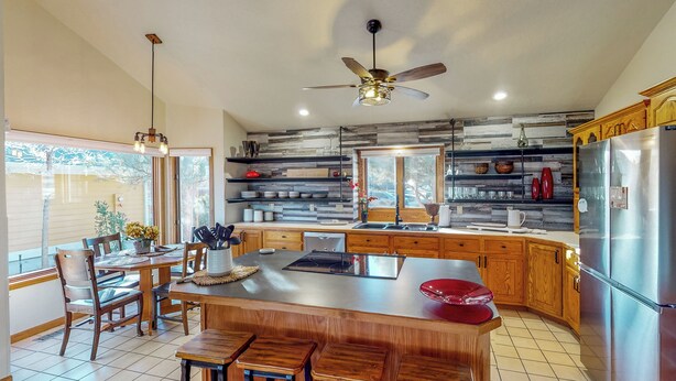 A modern kitchen with wooden cabinets, a large island, and a stainless steel refrigerator. - Lake-view, Dog-friendly 5BR w/ Fireplaces, Deck (Greeley)