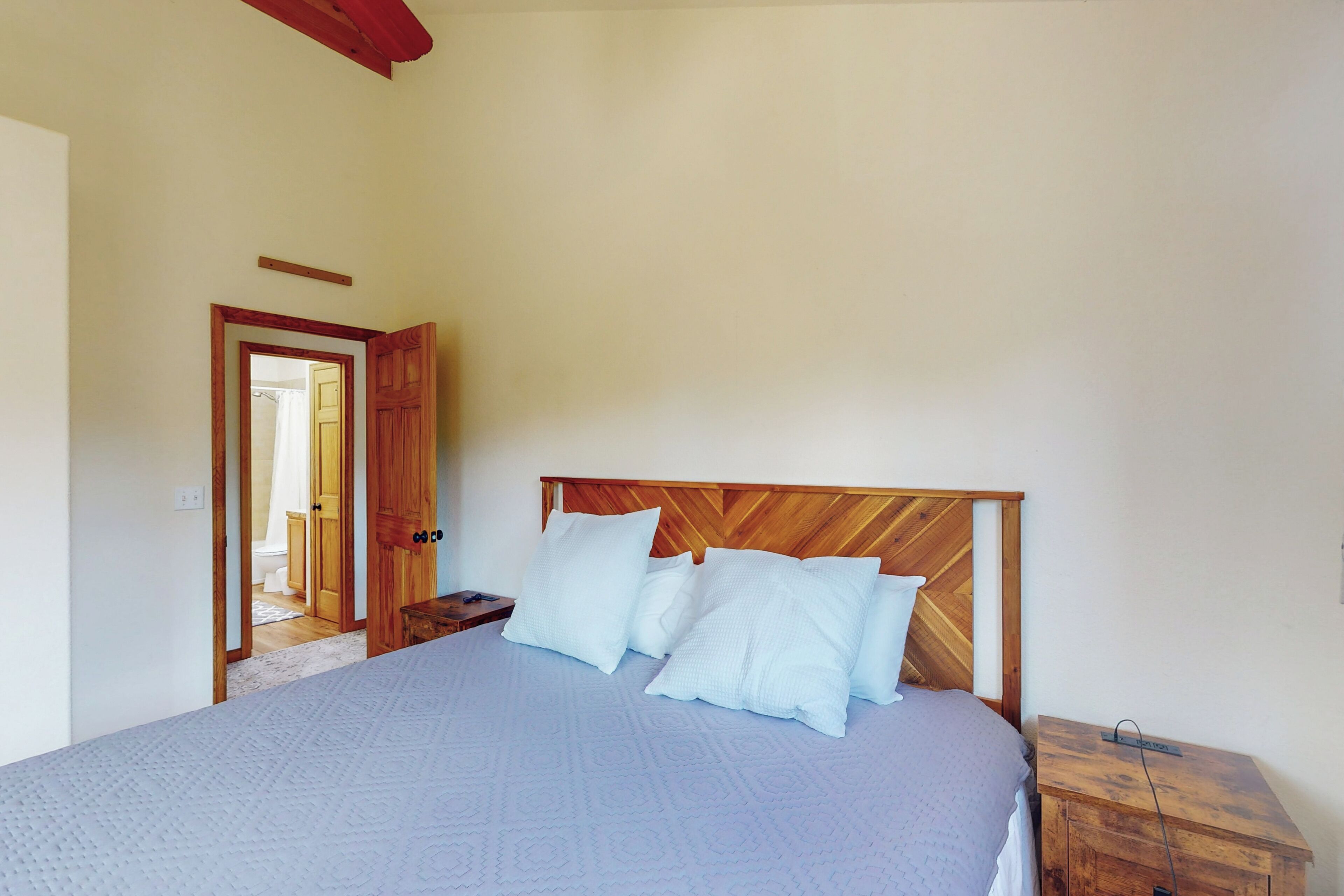 A bedroom with a large bed, wooden headboard, and a nightstand.