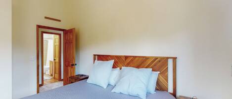 A bedroom with a large bed, wooden headboard, and a nightstand.