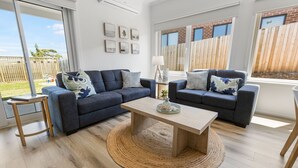 Ein modernes Wohnzimmer mit zwei Sofas, einem Couchtisch und einem kleinen Beistelltisch.