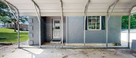 A covered porch with a concrete floor, a door, and a window.