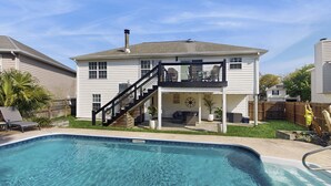 Ein zweigeschossiges Haus mit Pool, überdachter Terrasse und einer Treppe, die zu der oberen Etage führt.