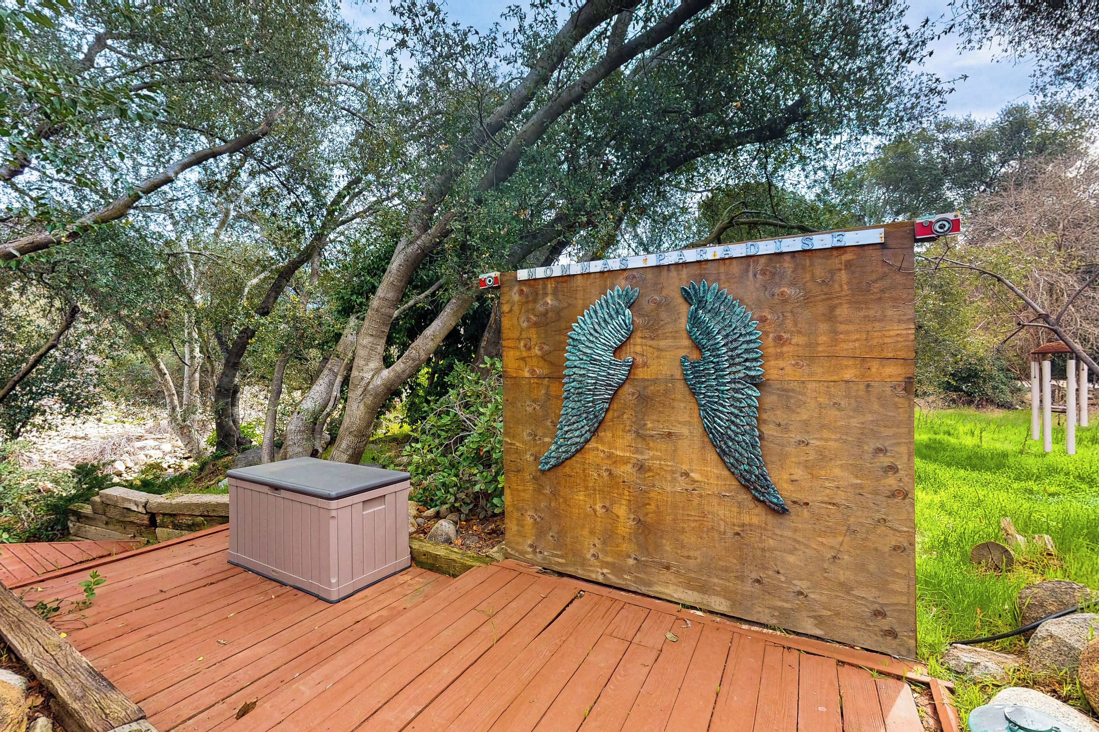 Una terraza de madera con un cerco de madera que presenta un diseño alado, un jacuzzi y un muro de piedra.