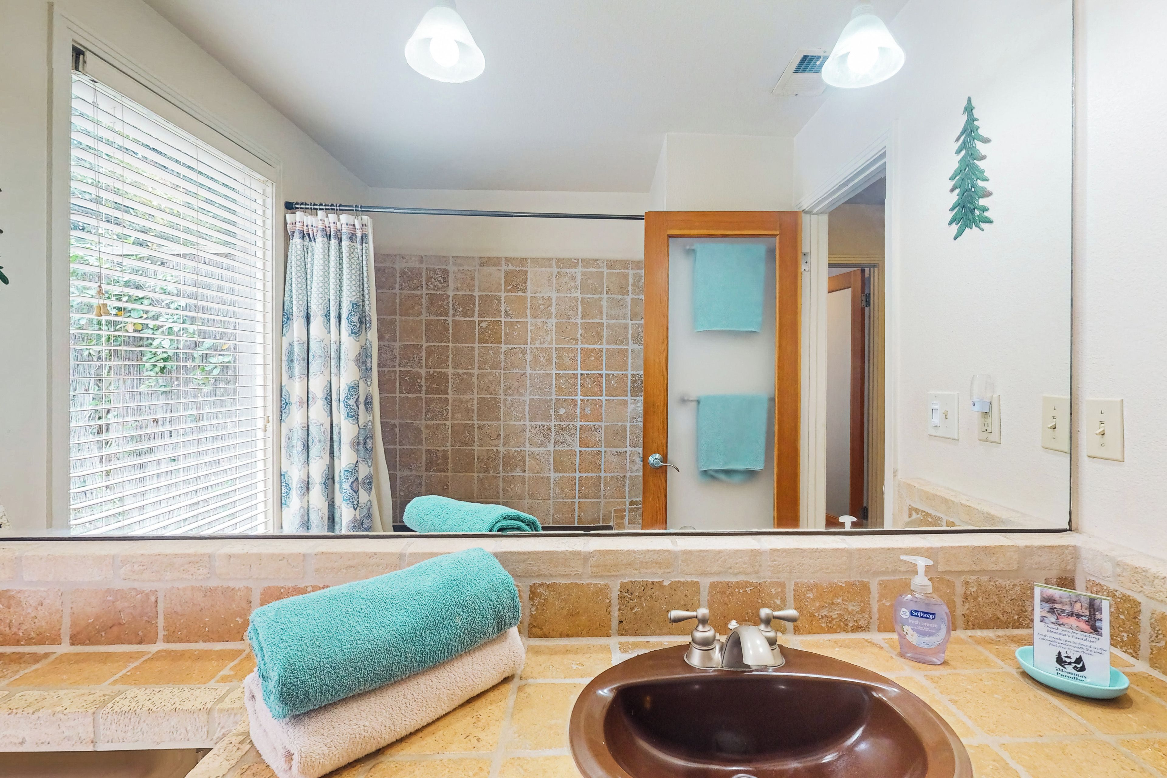 A bathroom with a large mirror, a sink, and a shower.