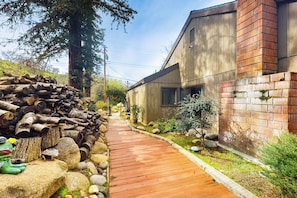 A wooden pathway leading to a modern building with a brick section and a wooden exterior. - Yard & Patio: Quiet & Well-stocked Riverside Home (Three Rivers)
