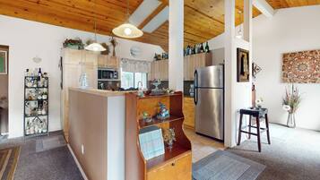 Una cucina con mobili in legno, un'isola centrale, un frigorifero e un lampadario.
