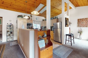 A kitchen with wooden cabinets, a central island, a refrigerator, and a hanging light fixture. - Yard & Patio: Quiet & Well-stocked Riverside Home (Three Rivers)