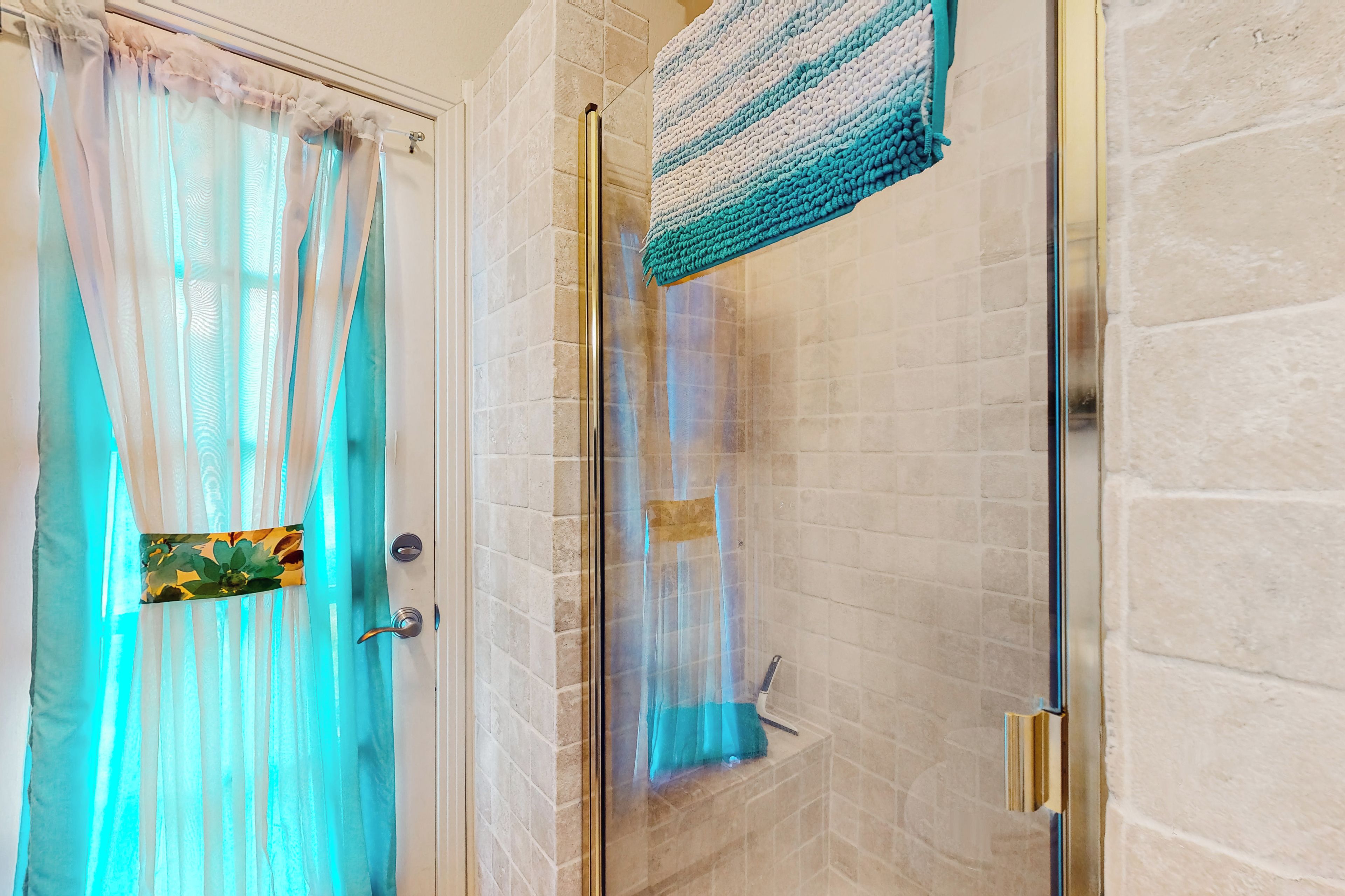 A bathroom with a glass shower door, a towel rack, and a shower curtain.