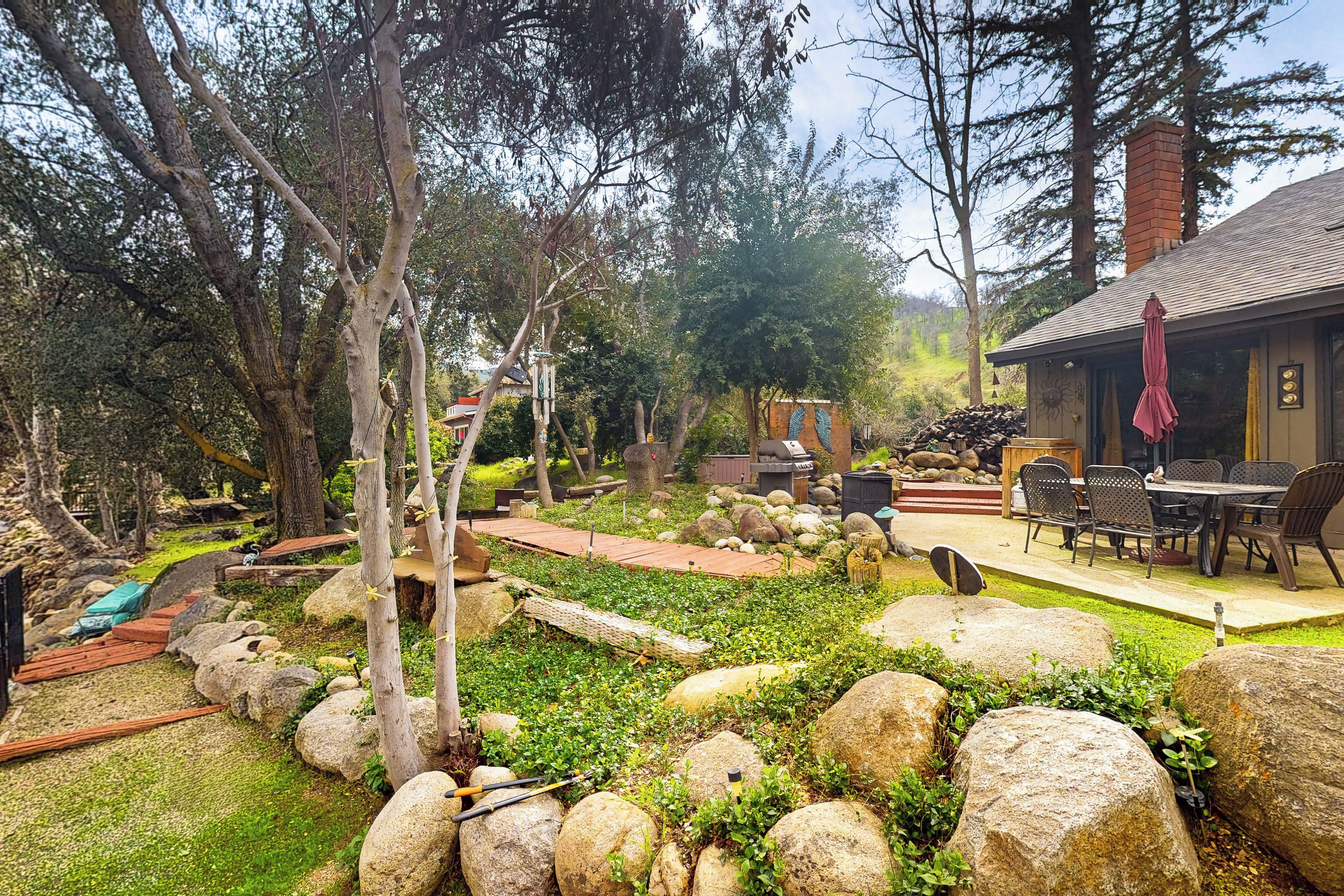 Un espace extérieur rustique doté d’une terrasse en bois, d’un chemin en pierre et d’un coin repas avec du mobilier d’extérieur.