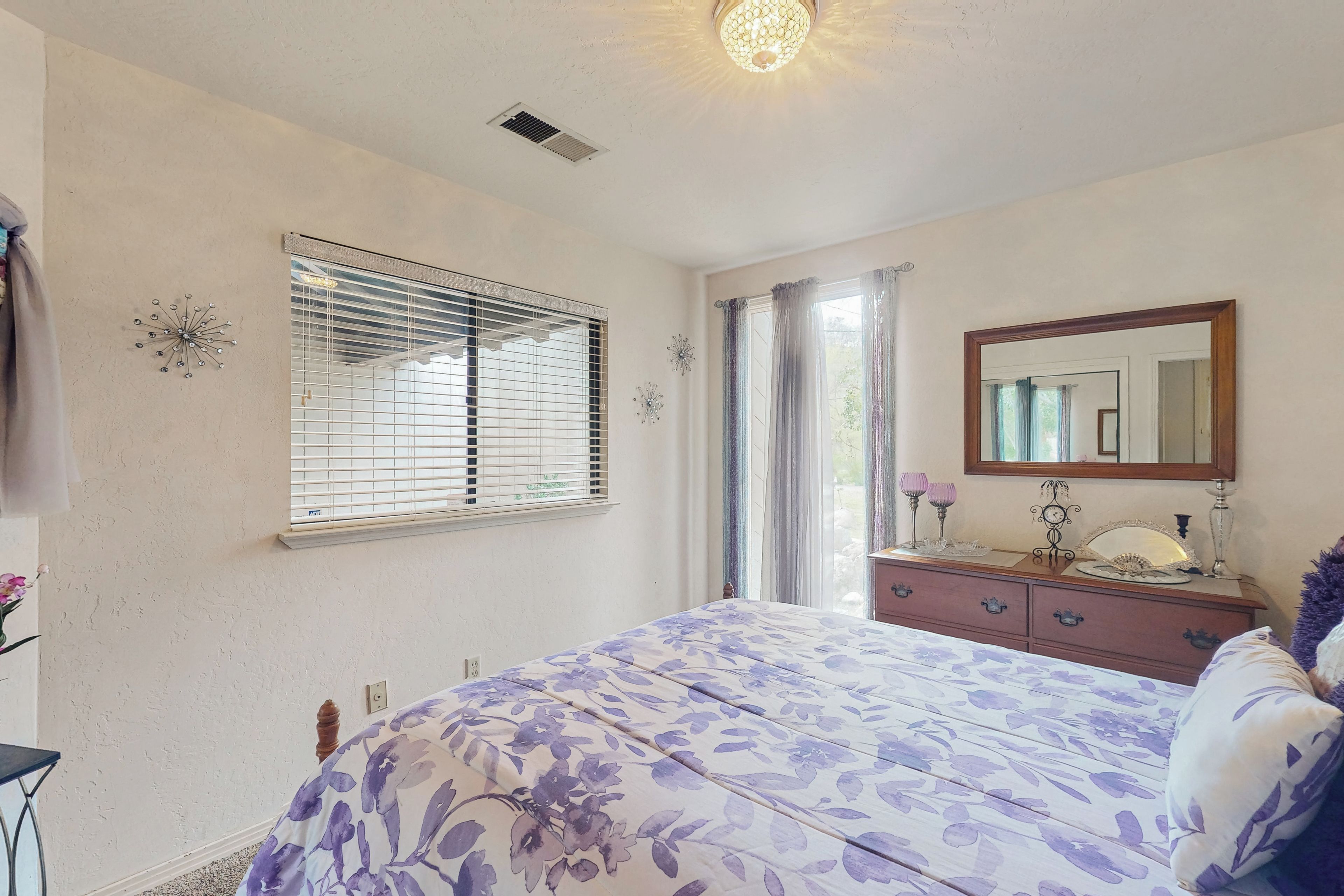 Un dormitorio con cama, cómoda, espejo y ventana con persianas.