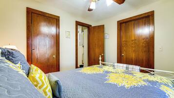 A bedroom with a bed, wooden doors, a ceiling fan, and a nightstand.