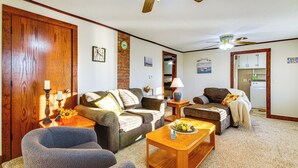 Ein Wohnzimmer mit Holztür, einer Couch, einem Couchtisch und einem Deckenventilator.