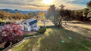 Uma casa com telhado azul, cercada por um gramado bem cuidado e árvores.