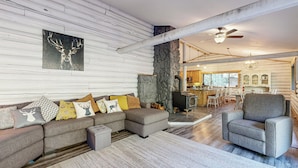 A modern living room with a sectional sofa, a fireplace, and a stone accent wall. - Kalama River View! Family-friendly Nature Escape (Kalama)