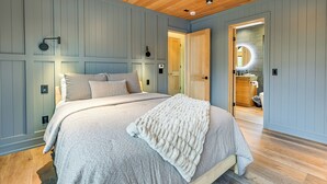 Ein Schlafzimmer mit einem großen Bett, Holzboden und einer Tür zu einem Badezimmer.