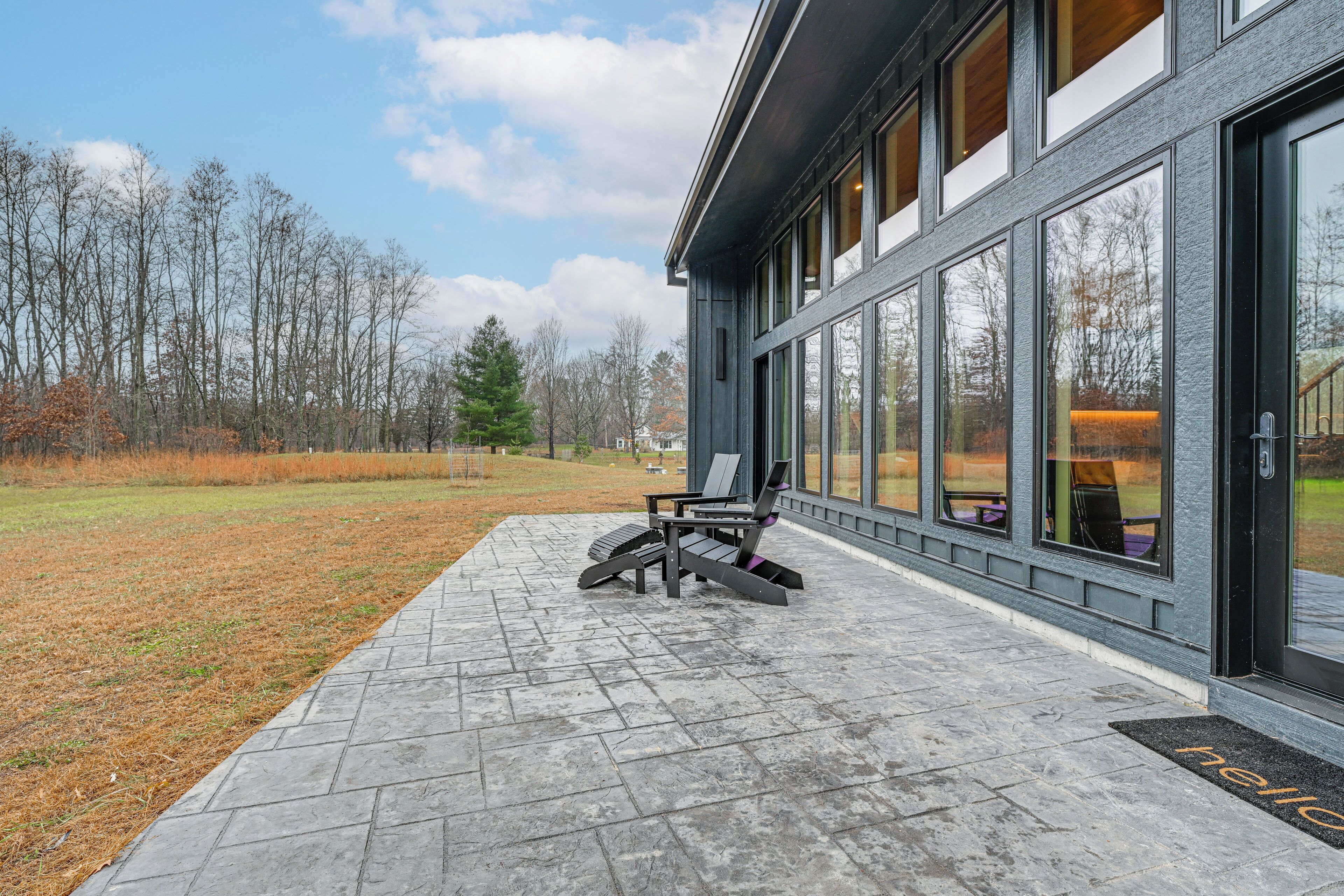 A modern building with large windows, a paved patio, and a chair outside.