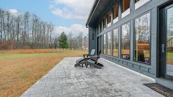 A modern building with large windows, a paved patio, and a chair outside.