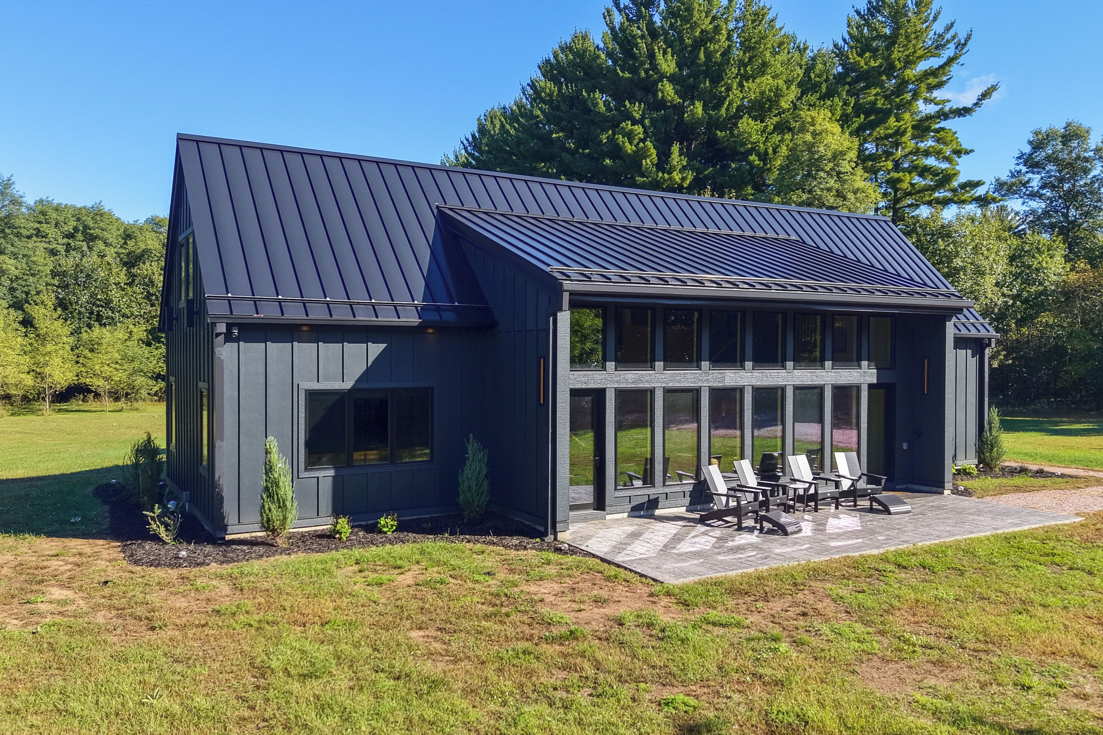 A modern building with a sloped roof, large windows, and a patio area with outdoor seating.