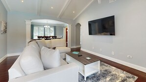 Ein Wohnzimmer mit einem weißen Ecksofa, einem Couchtisch und einem flachbildfernseher an der Wand.