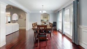Ein Essbereich mit Holztisch und Stühlen, einem weißen Sofa und einer Küche im Hintergrund.