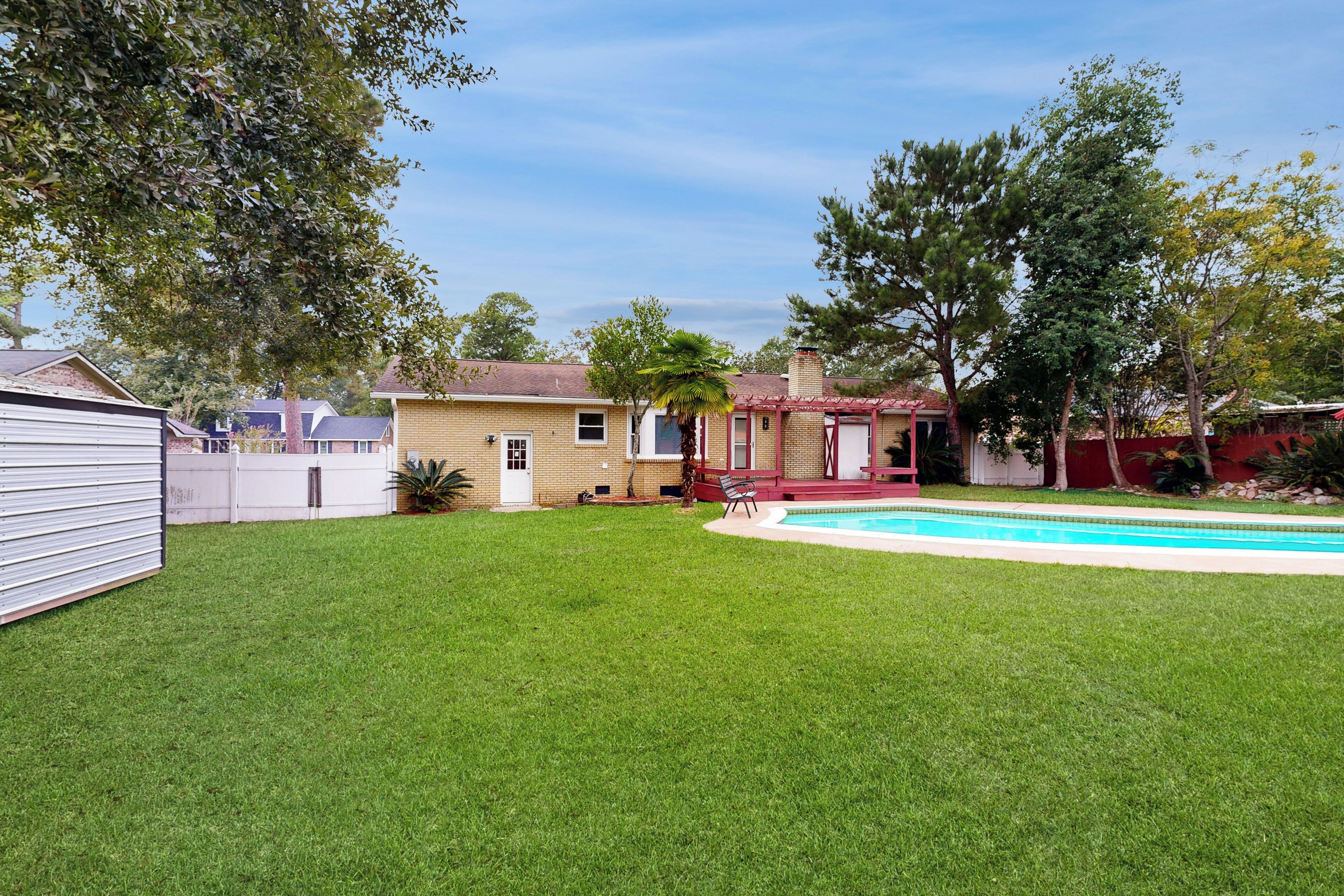 A backyard with a swimming pool, a house, and a fenced area.