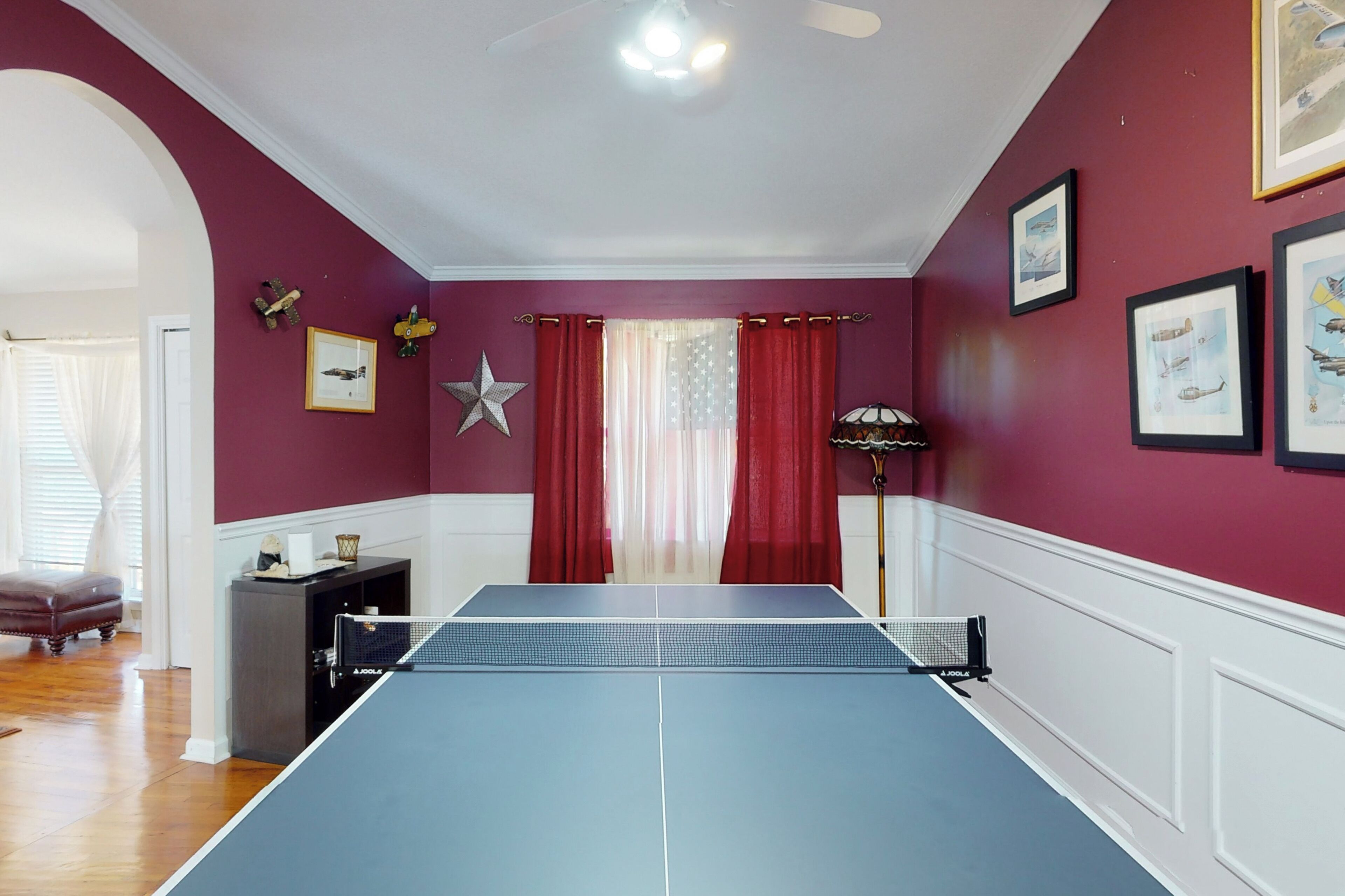 A room with a ping pong table, a star decoration, and framed pictures on the wall.