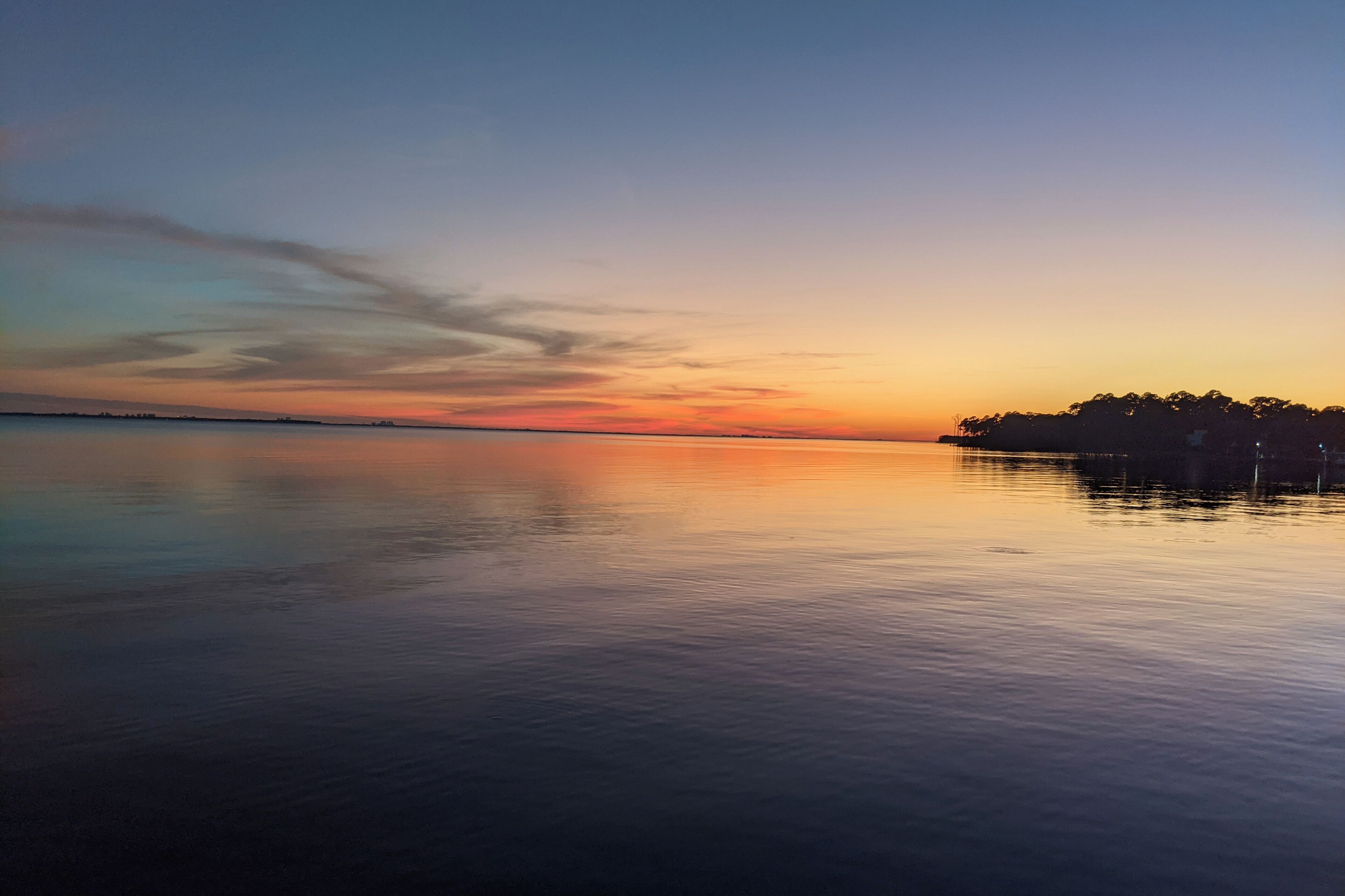 Ruhige Wasserfläche, die einen Sonnenuntergangshimmel spiegelt.