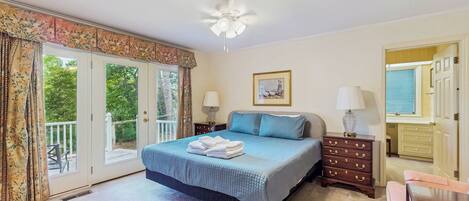 A bedroom with a bed, a dresser, a ceiling fan, and a window with curtains.