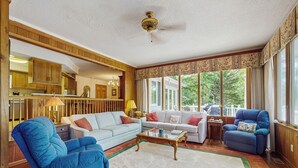 A spacious living room with a large window, a ceiling fan, and a view of the outdoors. - Deck & Private Dock! Waccamaw River Retreat (Conway)