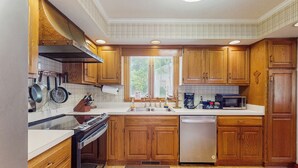 A kitchen with wooden cabinets, a stainless steel dishwasher, and a microwave. - Deck & Private Dock! Waccamaw River Retreat (Conway)
