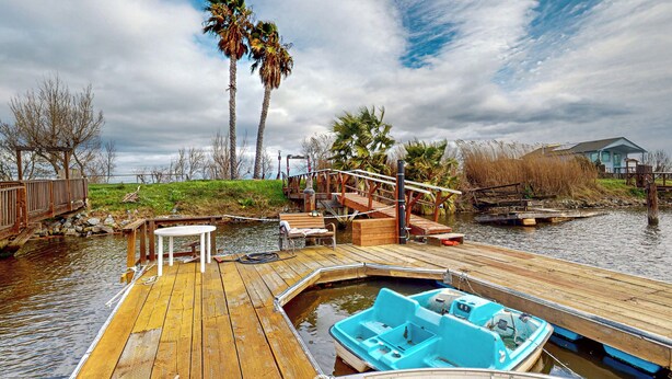 A wooden dock with a boat, a small table, and benches. - 3BR Dog-friendly Home Near River w/ Fire Pit (Bethel Island)