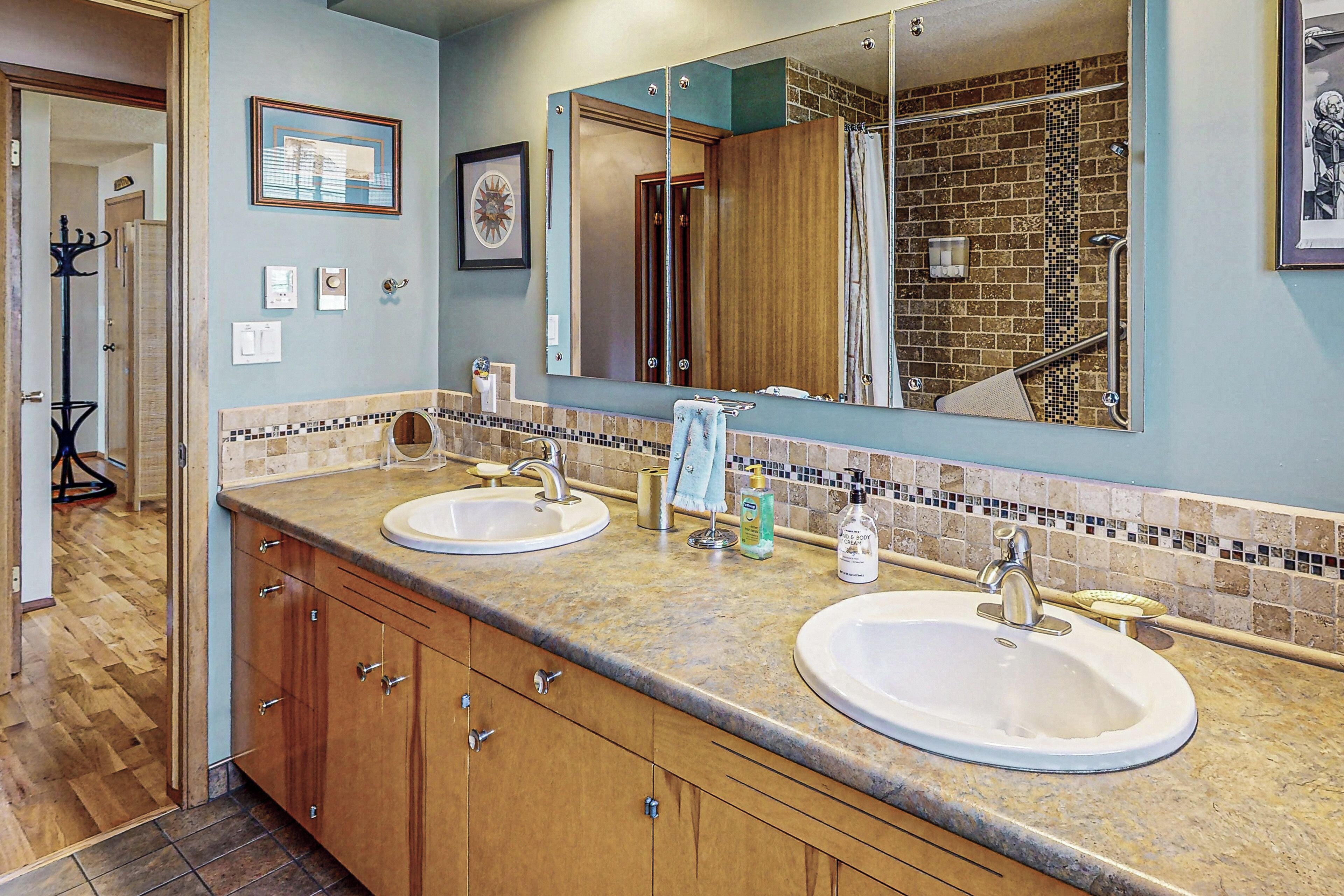 A bathroom with two sinks, a large mirror, and a shower area.